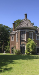 Een oud gebouw met toren en grasveld