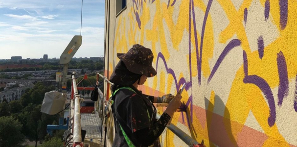 Kunstenaar Gleo is aan het werk aan de muurschildering