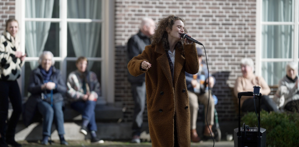 Zangeres zingend op een plein met kijkende mensen