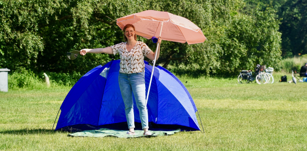 Killian voor een tent met een parasol op de Buurtcamping zuiderpark 
