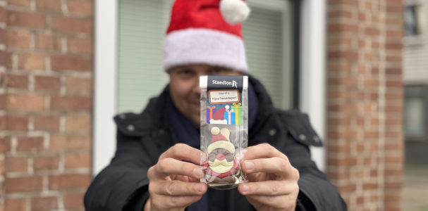 Medewerker van Staedion met kerstmuts op laat de kerstkransjes zien