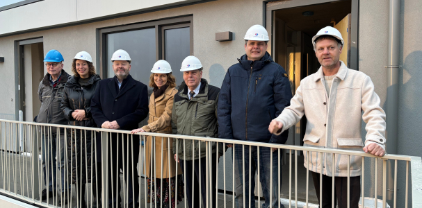 Groepsfoto van de deelnemers van de prestatieafspraken op een galerij met een helm op