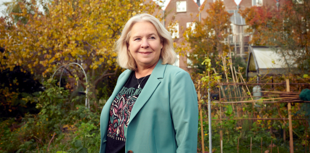 Antoinette gebiedsregisseur staat in een groene tuin de Spinozahof