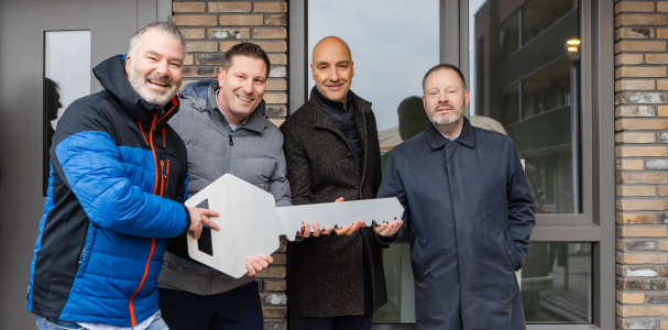 Een uitvergrootte sleutel van het appartementengebouw wordt in ontvangst genomen