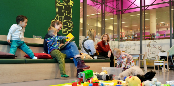 Moeders en kinderen spelen en lezen bij MIM