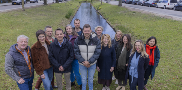 De ontwerpers van Studio Corvers, Overtreders W en Anne van Strien en Daniela Tokashiki gezamenlijk op de foto bij een groenstrook en water in de wijk