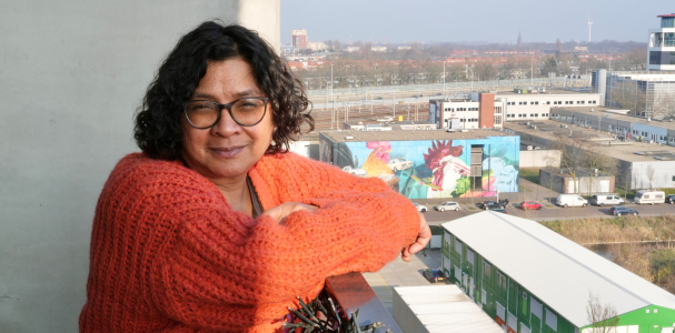 Bewoner Francine leunt over balkonreling 