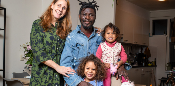 Gezin van vier personen. Vrouw, man en twee meisjes poseren in de woonkamer.
