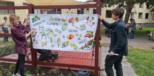 Twee personen hangen een doek op bij de nieuwe buitensalon in de binnentuinen van de Middenstede