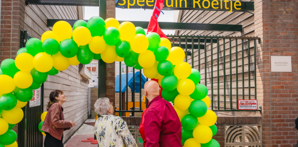 Twee dames en meneer onder een boog ballonnen en onthullen bord met naam Speeltuin Roeltje