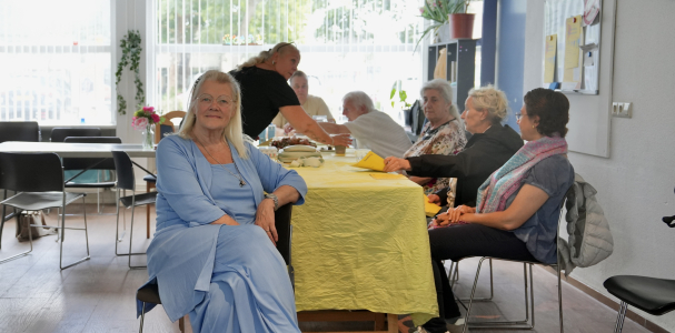 Een vrouw zit op een stoel voor een groep andere dames