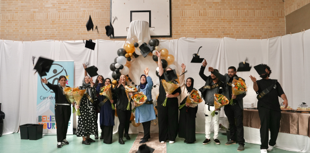 Een groep dames en heren gooien hun geslaagd hoedje in de lucht, ook houden ze bloemen vast