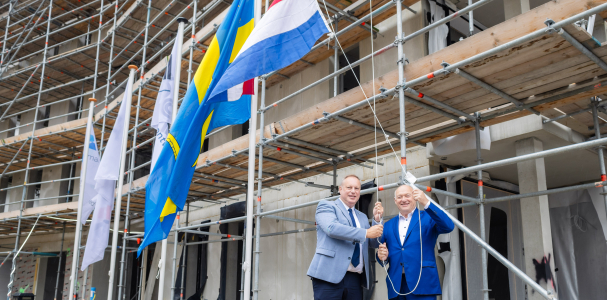Twee mannen hijsen de Nederlandse vlag