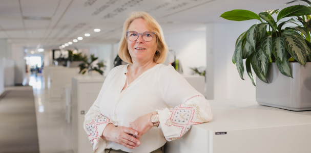 Mevrouw met handen over elkaar, leunt tegen kast