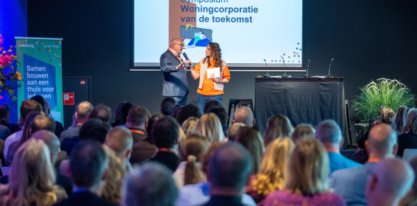 Jacques Thielen en dagvoorzitter Jessica Mendels op het podium bij het symposium Woningcorporatie van de toekomst