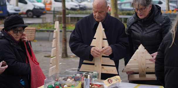 Bewoners versieren kerstboom bij de oliebolleactie in Ypenburg