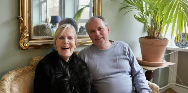 Buurvrouw Saskia en Buurman Ad zitten samen op een bank en lachen breeduit