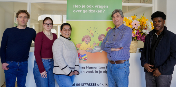 Vijf mensen van Humentum poseren bij een banner