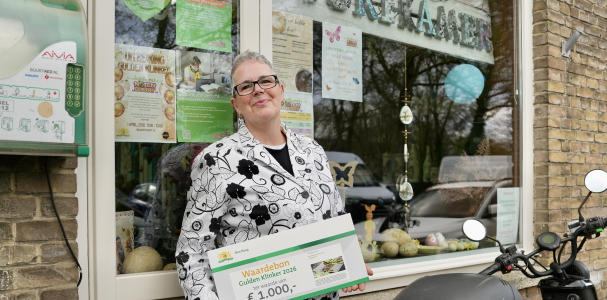 Lydia poseert voor haar Buurtkamer met de cheque van de Gulden Klinker.