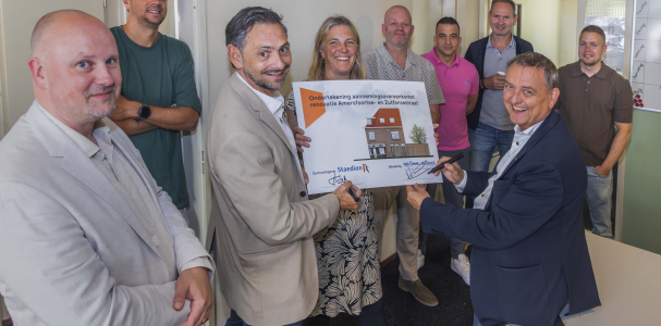 Kay Schellen en Olaf Lange ondertekenen een bord met daarop een afbeelding van het wooncomplex