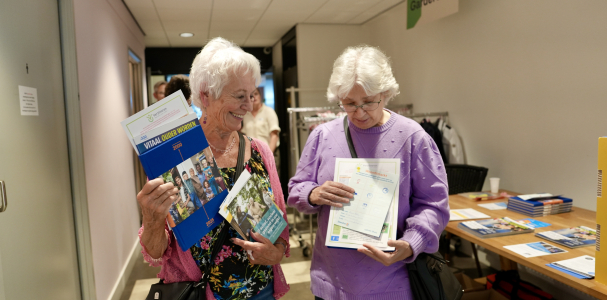 Twee dames op de Woonfitmarkt pakken wat folders