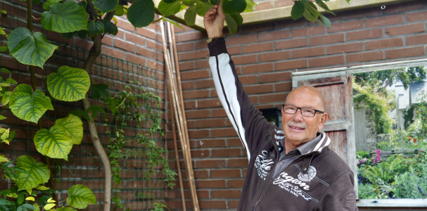 Henk staat in zijn tuin en laat zijn planten zien