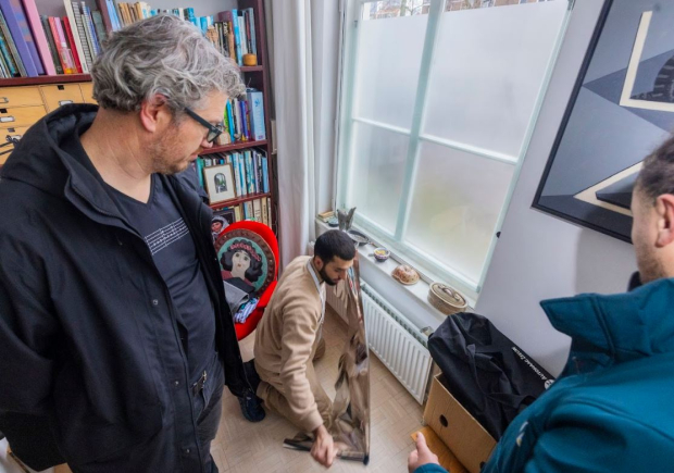 Wethouder Kapteijns kijkt hoe energiefikser Ramazan radiatorfolie aanbrengt bij een bewoner thuis