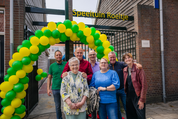 Zeven mensen onder een ballonnenboog voor Speeltuin Roeltje