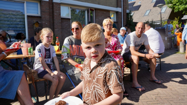 jongetje kijkt in camera met buurtgenoten op de achtergrond