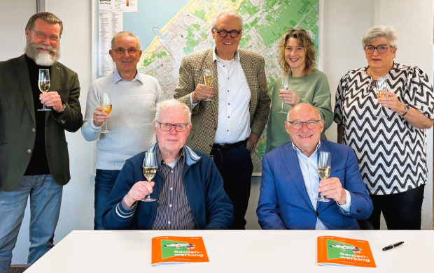 De leden van de huurdersvereniging heffen het glas na ondertekening van de overeenkomst