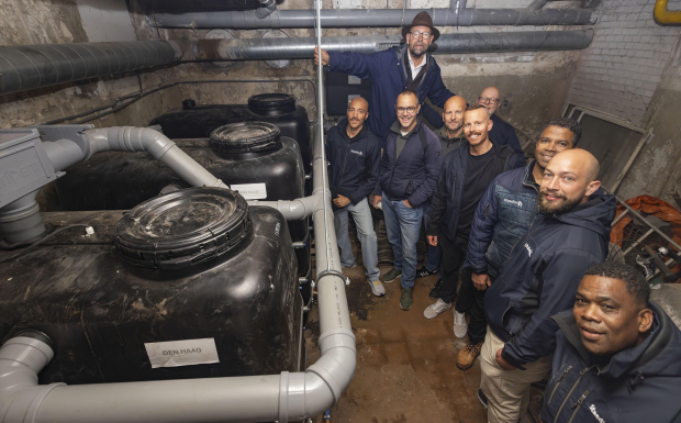 Collega's van Staedion staan bij de tank in de berging waar het regenwater wordt opgevangen.