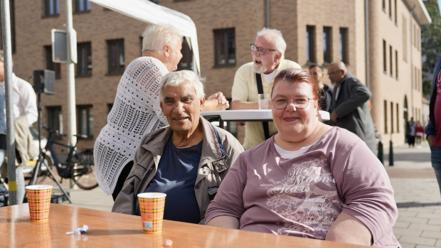 Twee bewoners zitten aan een tafel in de straat met een kopje koffie
