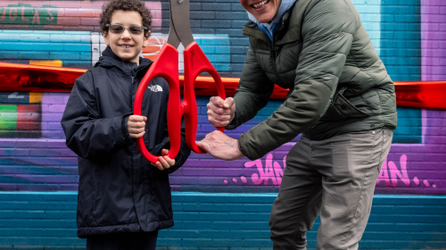 Kunstenaar Jan is de Man met jongen met schaar klaar om het lint te knippen