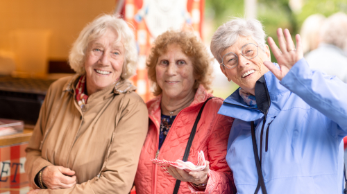 Gezelligheid bij de onthulling van de mural. Drie dames lachtent naast elkaar