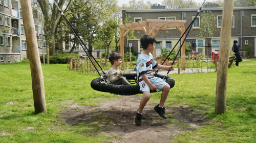 Kinderen op een schommel in de binnentuin Riddersdreef