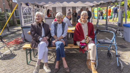Drie bezoekers aan picknick tafel tijdens het buurtfeest