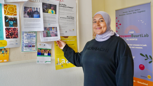 Dilan van het buurtlab bij een bord met flyers