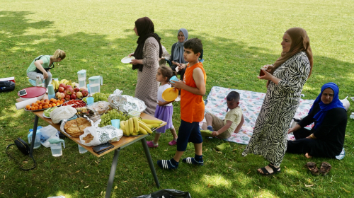 Kinderen en vrouwen bij een tafel vol eten tijdens de vrouwenpicknick