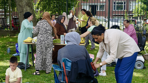Meerdere bezoekers van de zomerpicknick met elkaar in gesprek of aan het eten