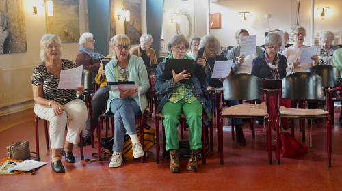 Koor Bosbesstraat aan het oefenen met muziekblad in hun handen