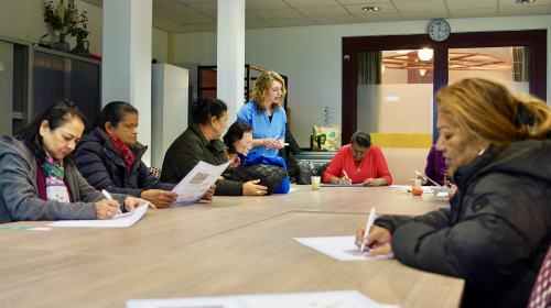 Les op in de infomarkt: bezoekers schrijven aan tafel
