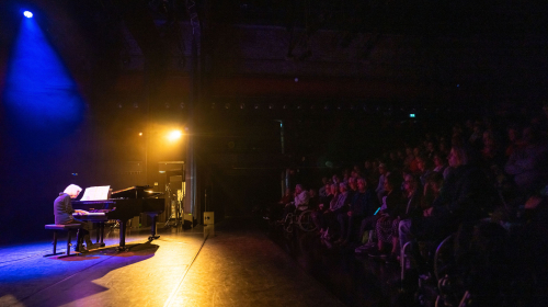 Optreden van een man achter een piano tijdens Regentes talentenshow 