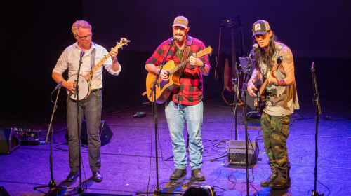 Optreden van drie mannen met een gitaar tijdens Regentes talentenshow 