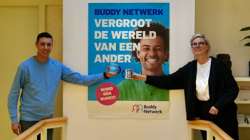 Buddy Netwerk - Ossie en Tessa voor een campagneposter en mok in hun handen