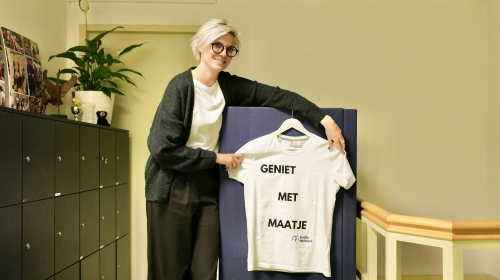 Tessa van buddy netwerk met een t-shirt in haar handen met de tekst 'geniet met maatje'