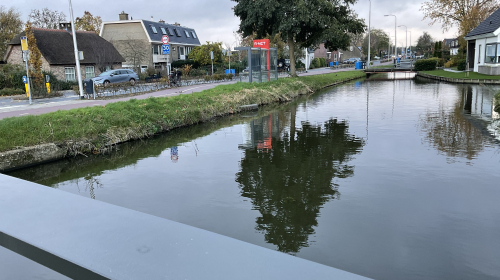 Entree naar de wijk: sloot met huizen op de achtergrond