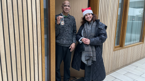 Medewerkers van Staedion delen kerstkransjes uit aan bewoner in deuropening