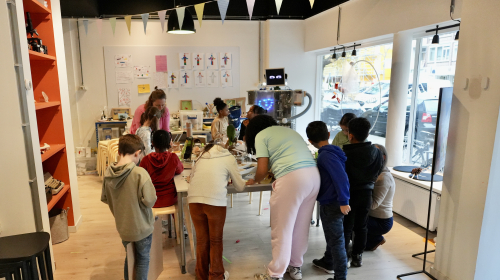 Een groep kinderen is onder begeleiding aan het werk rond een tafel bij het MuseumLab