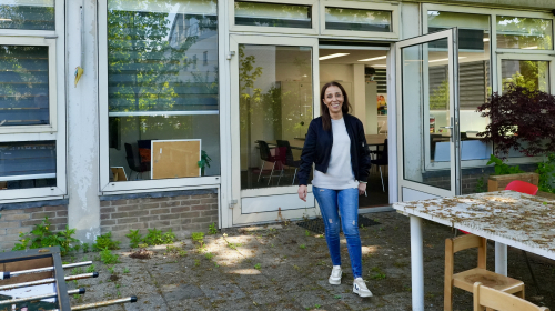 Mevrouw lacht en staat voor een gebouw.