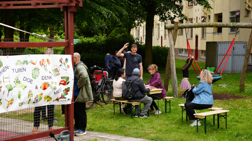 Bewoners zitten op bankjes in de binnentuin van de Middenstede bij de nieuwe buitensalon
